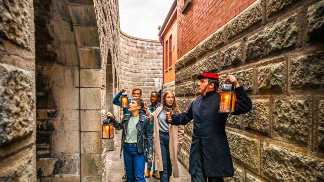 A military interpreter leading a ghost tour of the Halifax Citadel leads a group of visitors all carrying lanterns.