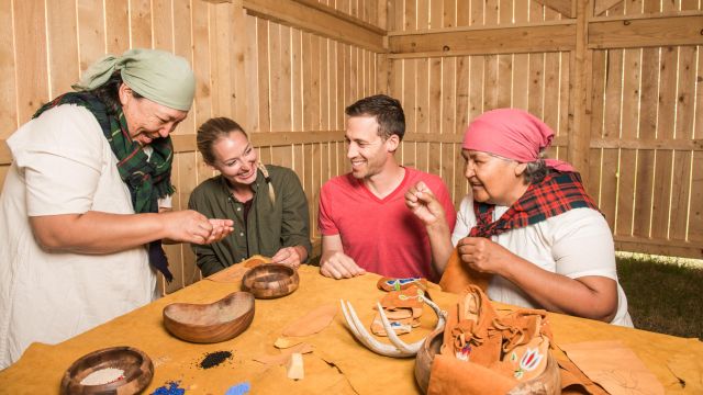 Two indigenous women teaching beading and leather crafts to two young adults inside the Boat House at Rocky Mountain House.