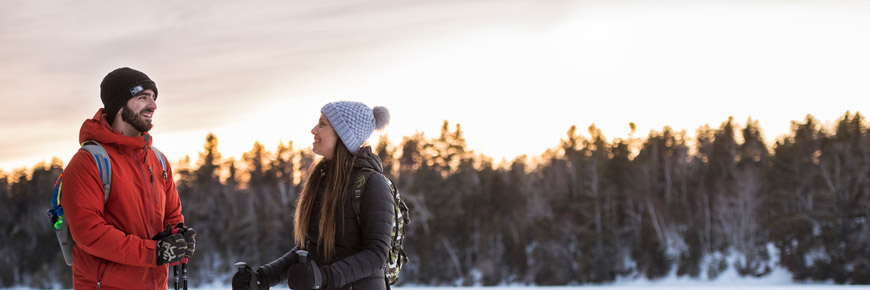 Two young adults on the frozen water at sunset.