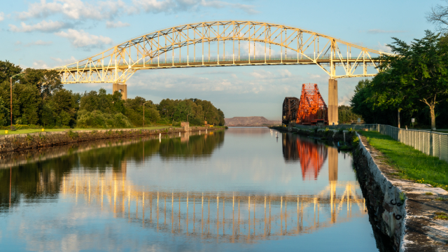 Bridge reflected in the still water of a canal on a calm day.