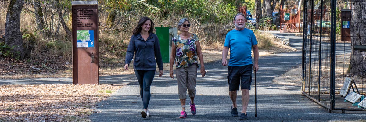 Trois adultes marchent sur un sentier accessible aux lieux historiques nationaux Fort Rodd Hill et du Phare-de-Fisgard.