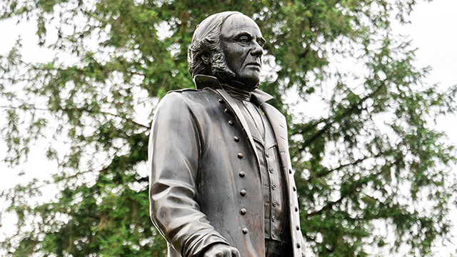 A statue of James Douglas with trees in the background