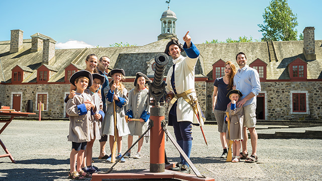 A costumed guide with two families of visitors and children dressed as soldiers in the inner courtyard