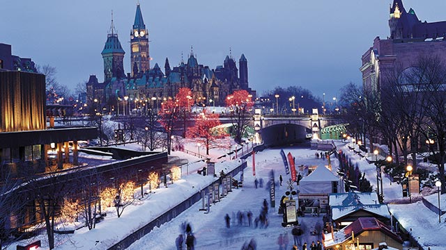 The Rideau Canal Skateway at night with city lights and buildings in the background.