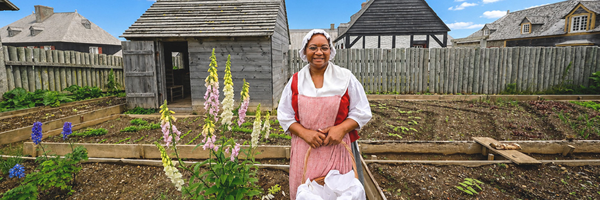 A guide wearing a period costume in a heritage garden at Fortress of Louisbourg National Historic Site