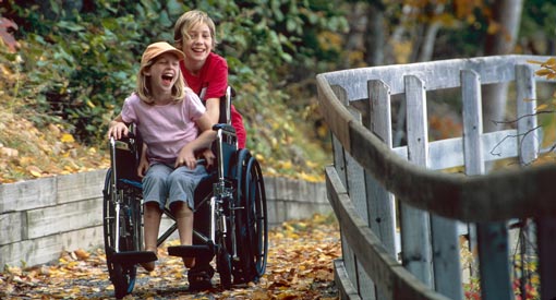 Two young visitors, including one in a wheelchair, hike the accessible Freshwater Lake Trail.