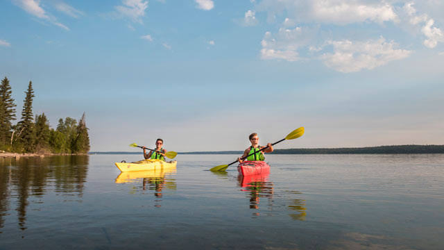 Two visitors explore Clear Lake in their kayaks in Riding Mountain.