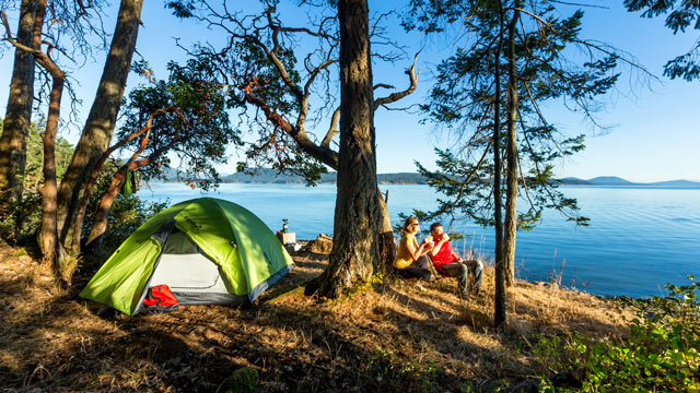 Two campers relax at their scenic waterfront campsite at Arbutus Point at Gulf Islands.
