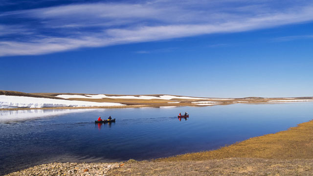 Two canoes on the Thomsen River with snow and tundra in the background at Aulavik.
