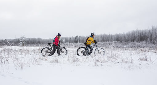Deux cyclistes font du vélo à pneus surdimensionnés en hiver.