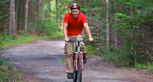 A man rides his bike on a forest road.