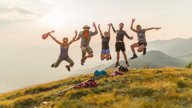  Five young adults jumping for a photo on the top of Opal Hills in Jasper National Park.