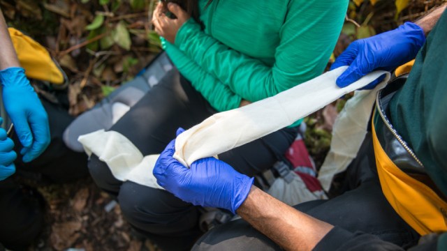  Two people sling an injured woman with first aid equipment.