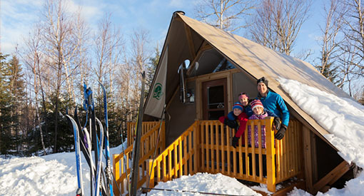 A small family posing for the camera on the patio of the Otentik tent.