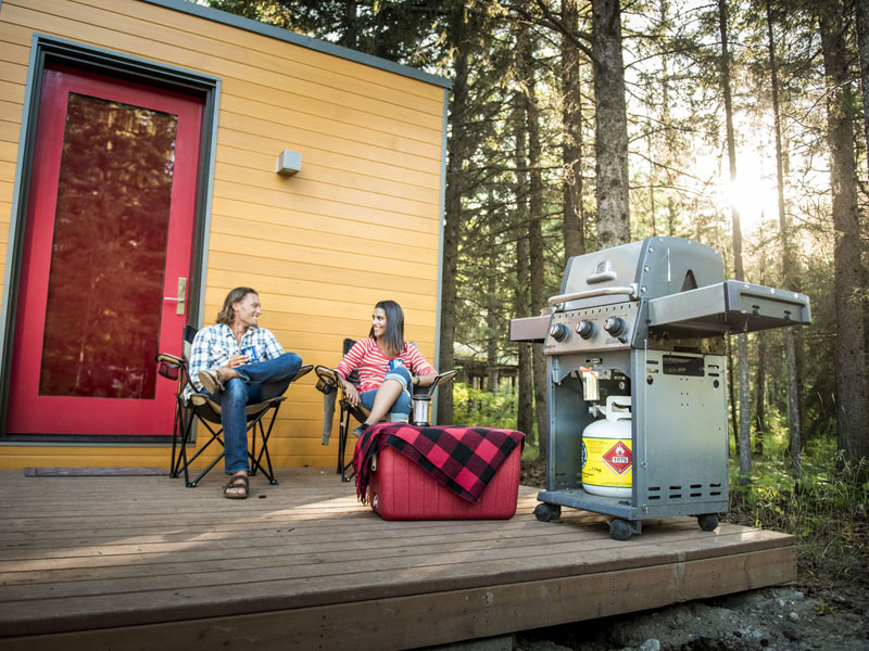 Visitors relax on the deck outside a MicrOcube at Wasagaming Campground.