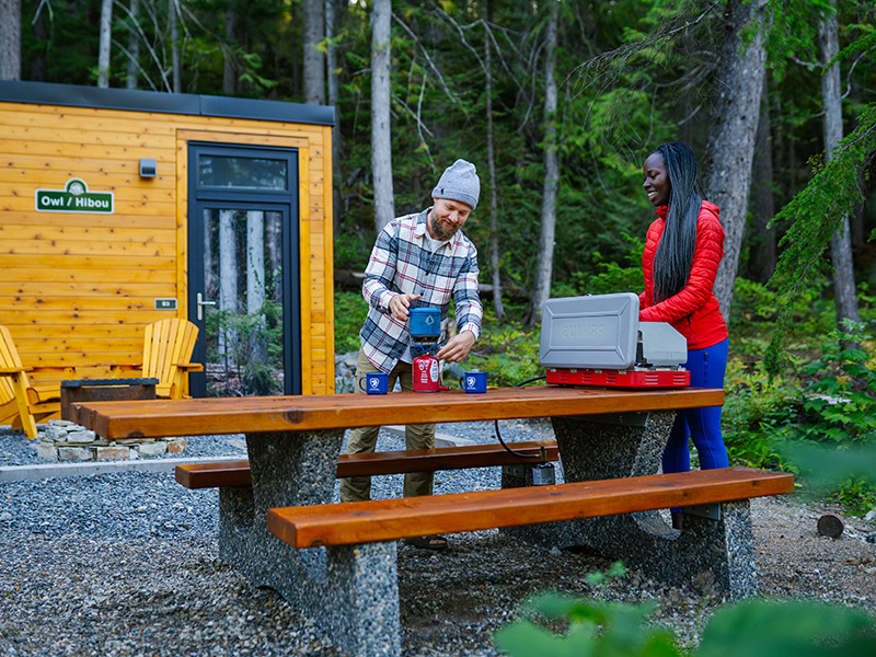 Un couple prépare du café sur la table de pique-nique du MicrOcube au parc national du Mont-Revelstoke