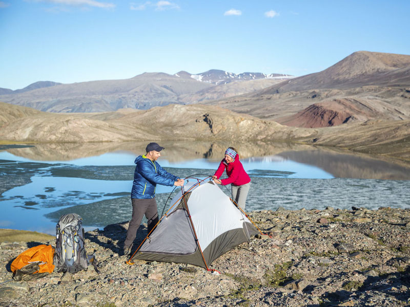 Deux visiteurs établissent leur campement en bordure de l'eau dans le secteur Omega Lakes.