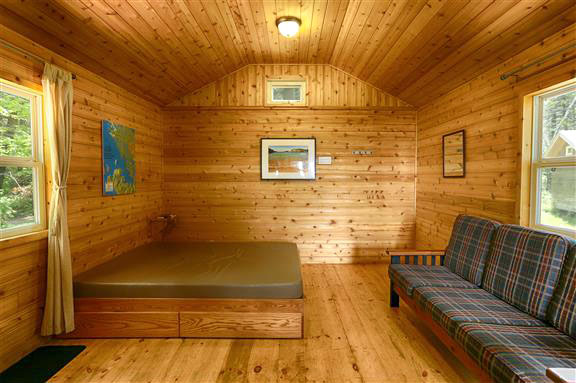 A bed and a couch inside a cabin.