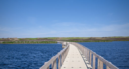 Two visitors resting along a floating boardwalk to the sand dunes.