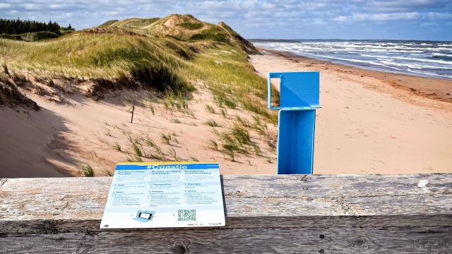 Une station bleue « Coastie » pour prendre des photos est installée sur un belvédère avec une vue sur la page et la dune.