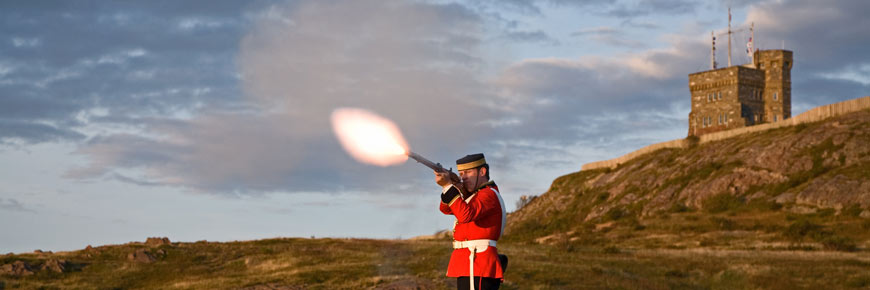 A man shoots a musket on a hill.