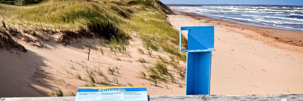 Une station bleue « Coastie » pour prendre des photos est installée sur un belvédère avec une vue sur la page et la dune.