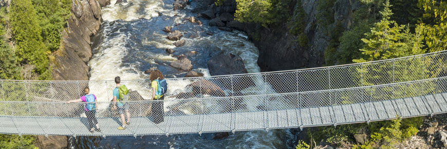 Des visiteurs admirent la vue à partir du pont suspendu de la rivière White, près des chutes Chigamiwinigum.