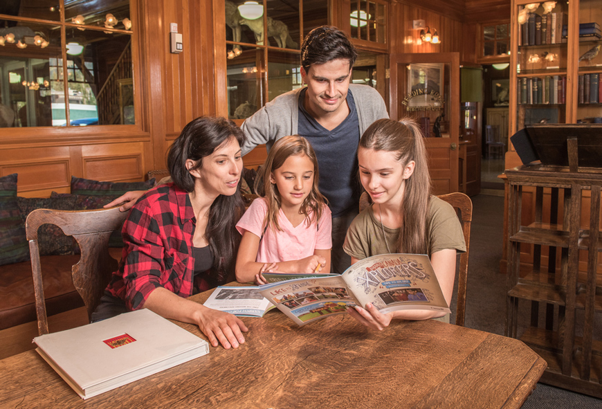 A family enjoys the Xplorers activity booklet inside the museum's reading room