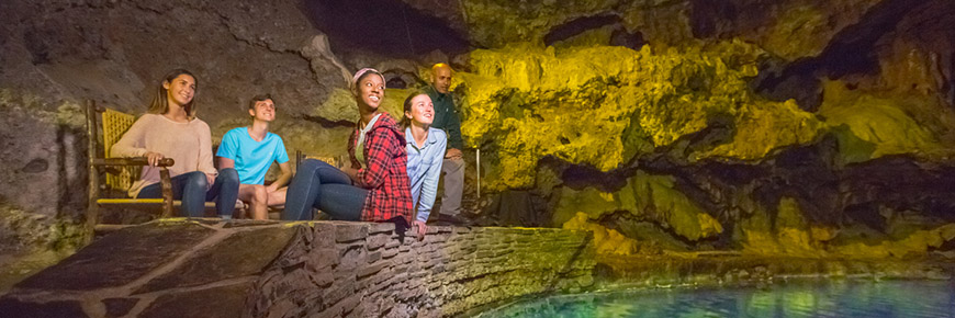 Visitors sit by the turquoise thermal waters in the Cave and Basin cave