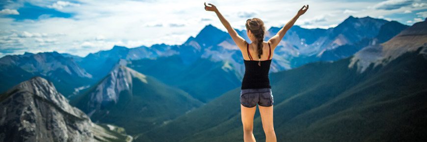 A young woman at the peak of the Sulphur skyline trail with her arms outstretched