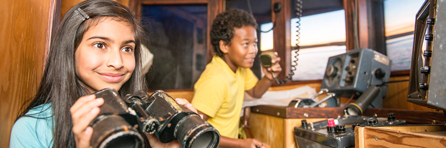 Deux enfants jouent au capitaine et au pêcheur dans une réplique du pont d’un chalutier