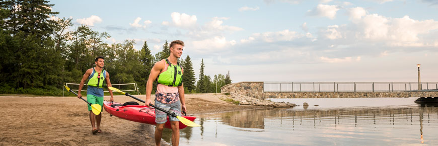 Des visiteurs mettent à l’eau leur kayak sur la plage principale du lac Clear à Wasagaming. 