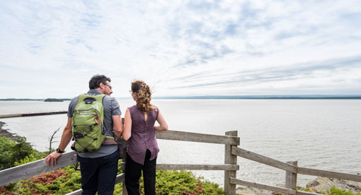 Two visitors at a lookout facing the St. Lawrence River.