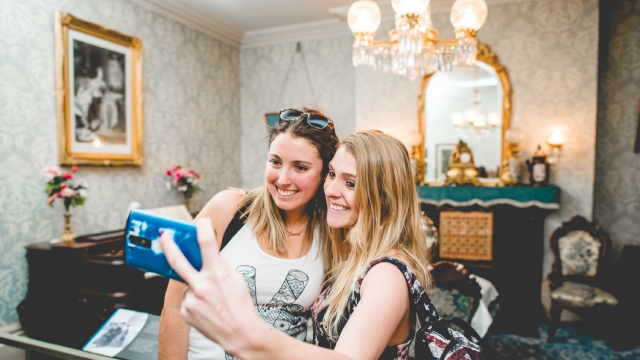 Two young women taking a selfie in a Victorian-style room.