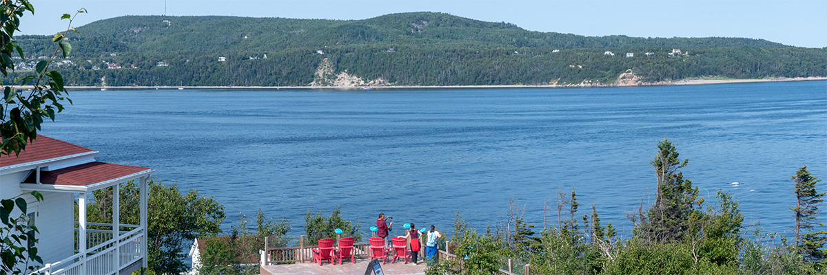 Des visiteurs à l’extérieur du Centre d'interprétation et d'observation de Pointe-Noire observent un béluga.