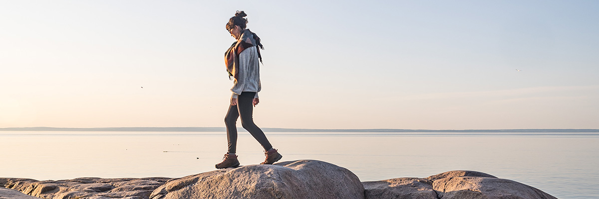 A woman walking on the rocks along the water outside the Cap-de-Bon-Désir Interpretation and Observation Centre.