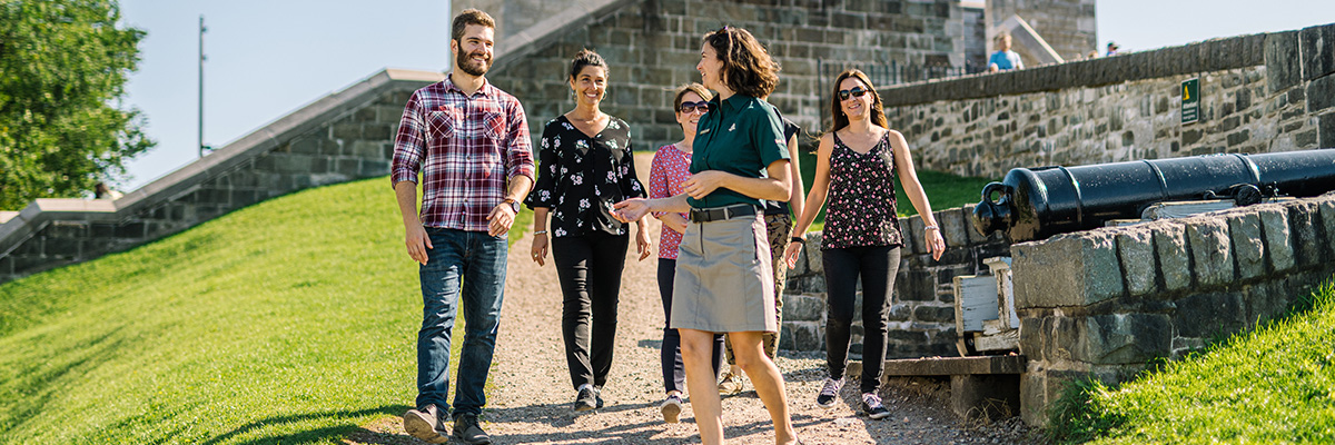 A guide with four visitors outside the Fortifications of Québec historic site.