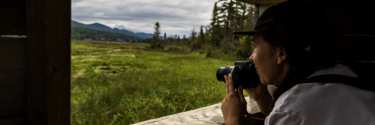Un visiteur avec un appareil photo dans la cache de Penouille à Forillon.