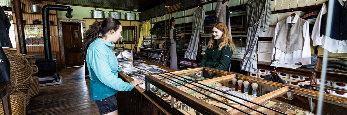 A young woman talking with an employee behind the counter at the Hyman & Sons General Store.