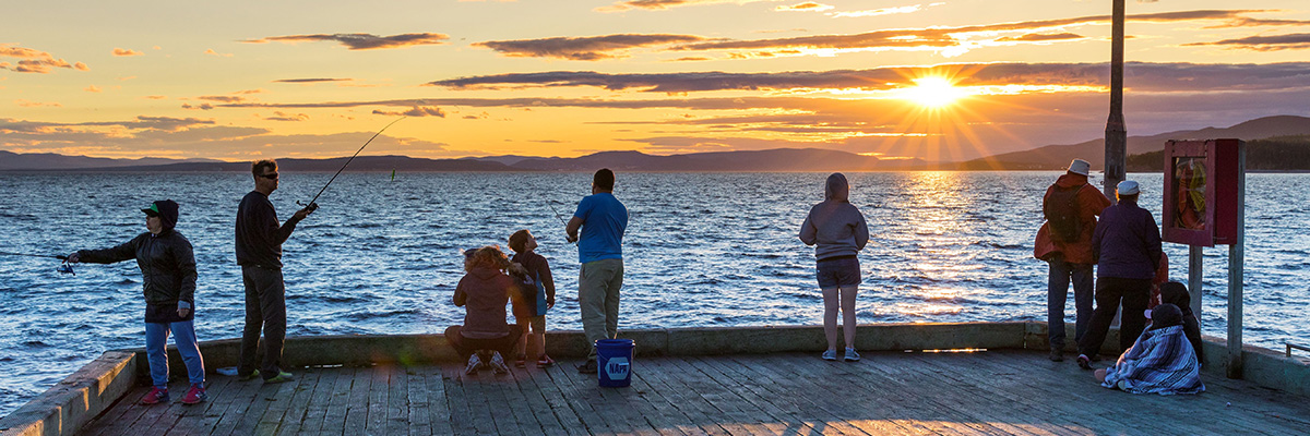 Visitors fishing on the Grande-Grave wharf at sunset in Forillon.