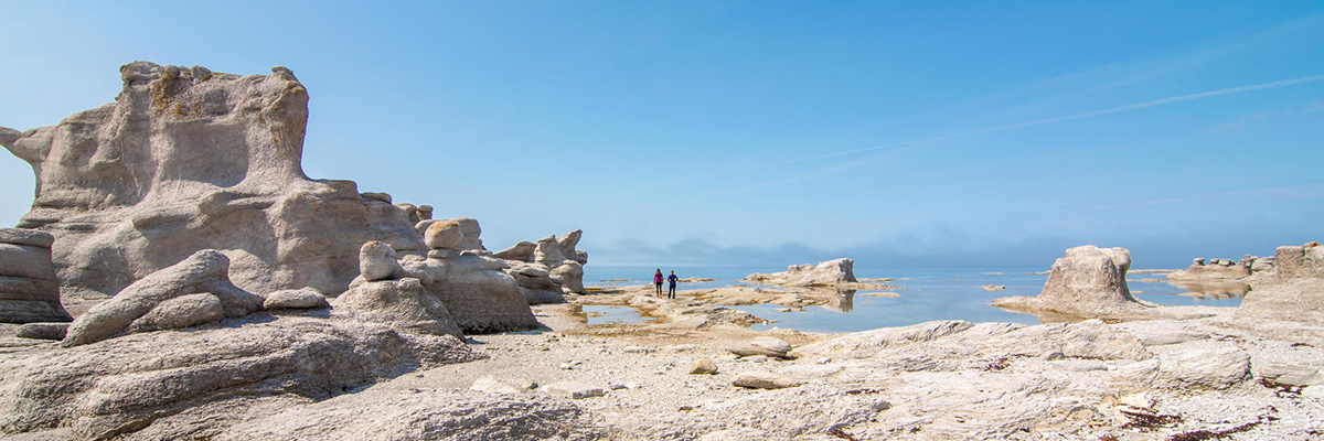 Two visitors walking on the rocks with monoliths in close-up in the Mingan Archipelago.