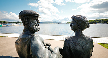 Une statue d'Alec et Mabel Bell au bord de l'eau.