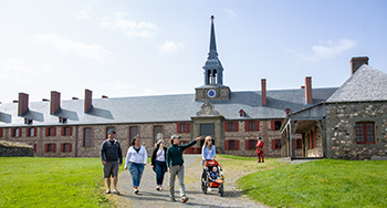 Un groupe de personnes avec un guide marchant devant le bastion du Roi à la forteresse de Louisbourg.