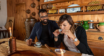 Deux personnes assises à une table avec des tasses de chocolat chaud dans une salle à manger d'époque de la forteresse de Louisbourg.