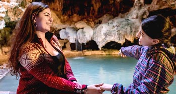 Mère et fille assis à côter d'une piscine sous-terrain se tenant la main