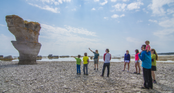 An employee from Parks Canada is talking to a group of visitors, with kids, near a monolith