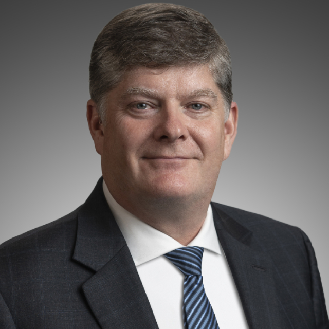 Headshot of Parks Canada President and CEO Ron Hallman. He has blue eyes and gray hair and is wearing a suit and tie.