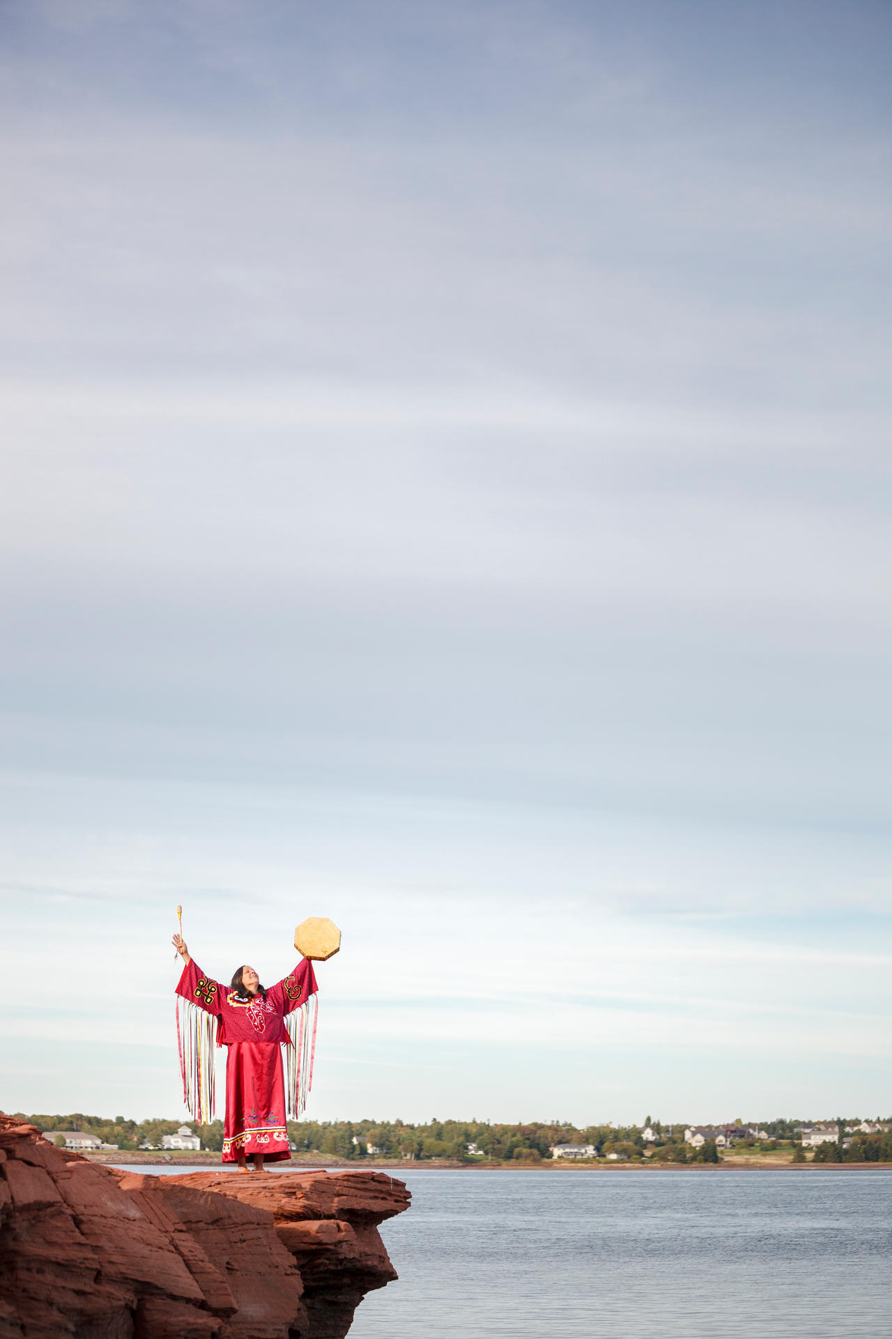 Une femme Mi'kmaq joue du tambour sur une falaise surplombant l’embouchure de la rivière Hillsborough. Lieu historique national de Skmaqn–Port-la-Joye–Fort-Amherst. 