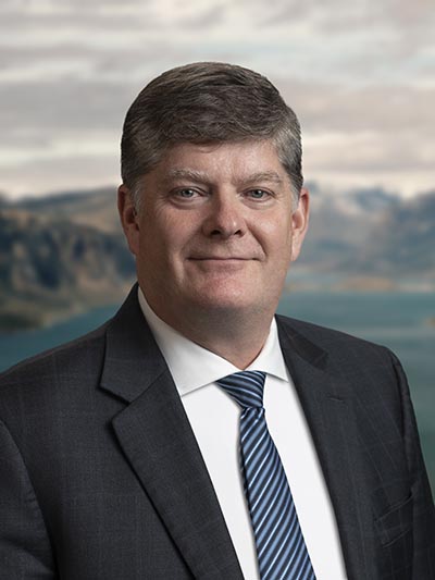 Photo du Président et directeur général de Parcs Canada, Ron Hallman. Il a les yeux bleus et les cheveux gris et porte un costume et une cravate.