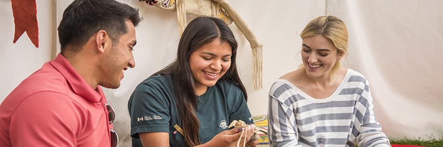 A Parks Canada interpreter shows visitors Indigenous artifacts as part of the Anishinabe cultural workshop program. Riding Mountain National Park.